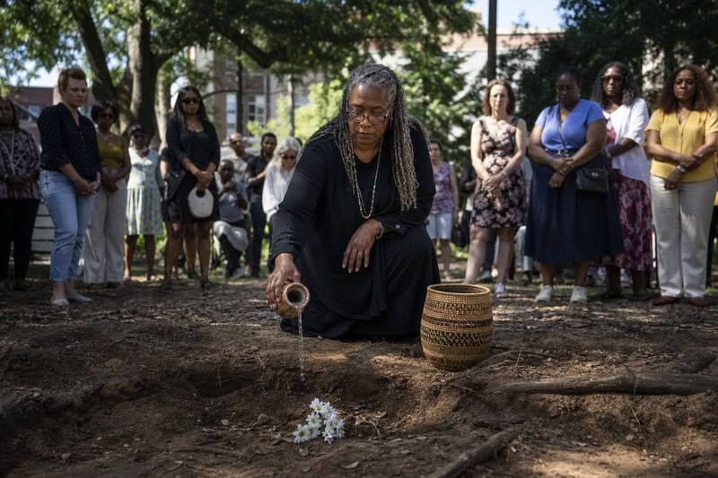 A figure performs a water ceremony over a burial site where enslaved people lie beneath a Charleston street slated for&hellip;