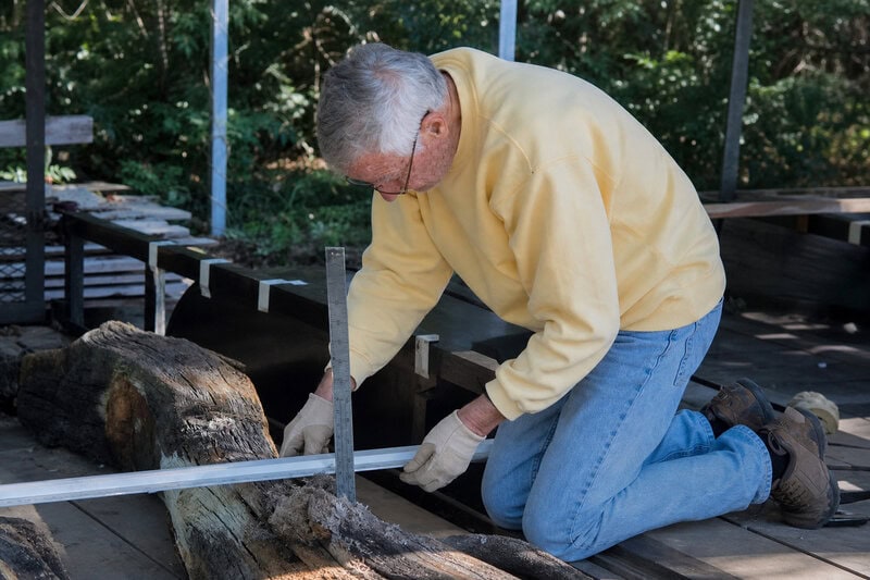 A maritime archaeologist measures timber dimensions from the unidentified Nantucket wreck