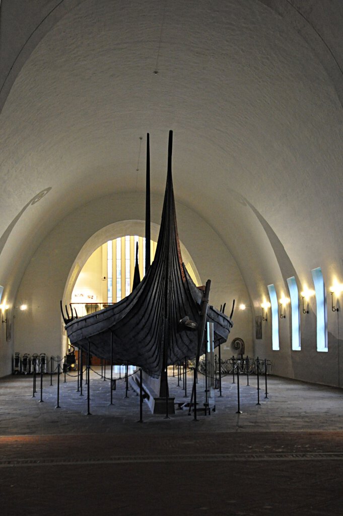 The Oseberg ship is a real Viking ship burial vessel displayed in dramatic museum lighting, directly illustrating the&hellip;